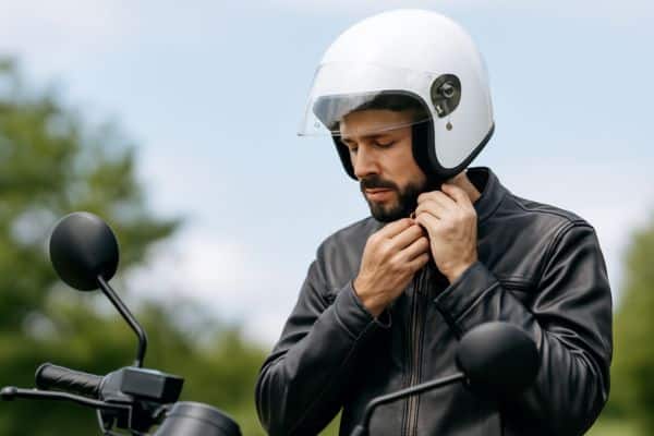 Motociclista ajustando capacete em um dia ensolarado, reforçando a responsabilidade e proteção com seguro ideal para moto