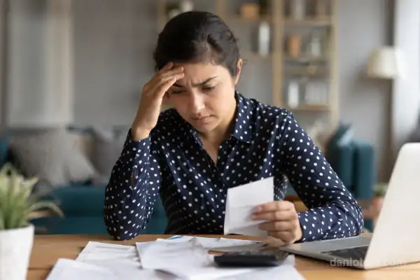 Antecipar FGTS para quitar dívidas em 2026 com pessoa preocupada analisando contas, comprovantes e calculadora sobre a mesa