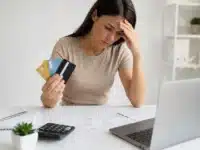 Mulher preocupada analisando contas e cartões de crédito enquanto busca como sair das dívidas do cartão em 2026.