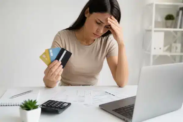 Mulher preocupada analisando contas e cartões de crédito enquanto busca como sair das dívidas do cartão em 2026.